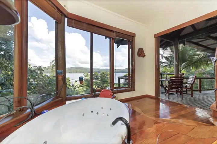Possums treehouse spa bath beside windows looking over Lake Baroon