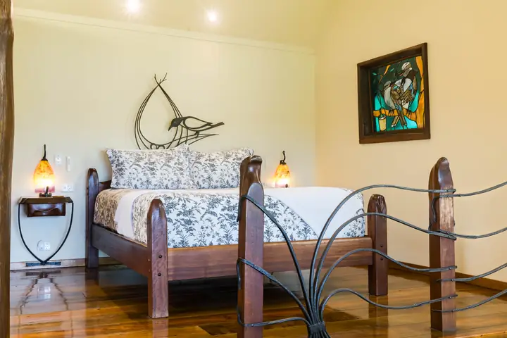 Bedroom in The Bower with a carved timber bed and sculptural metalwork
