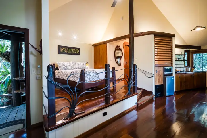 Two Frogs treehouse with a carved timber bed under a pitched ceiling
